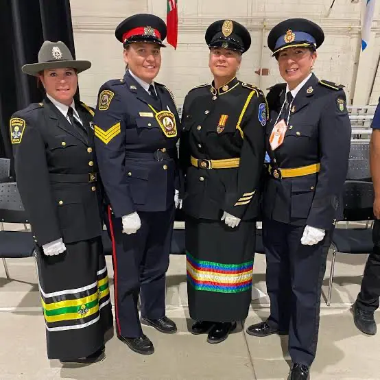 Four officers in formal uniforms with colorful regalia standing together.