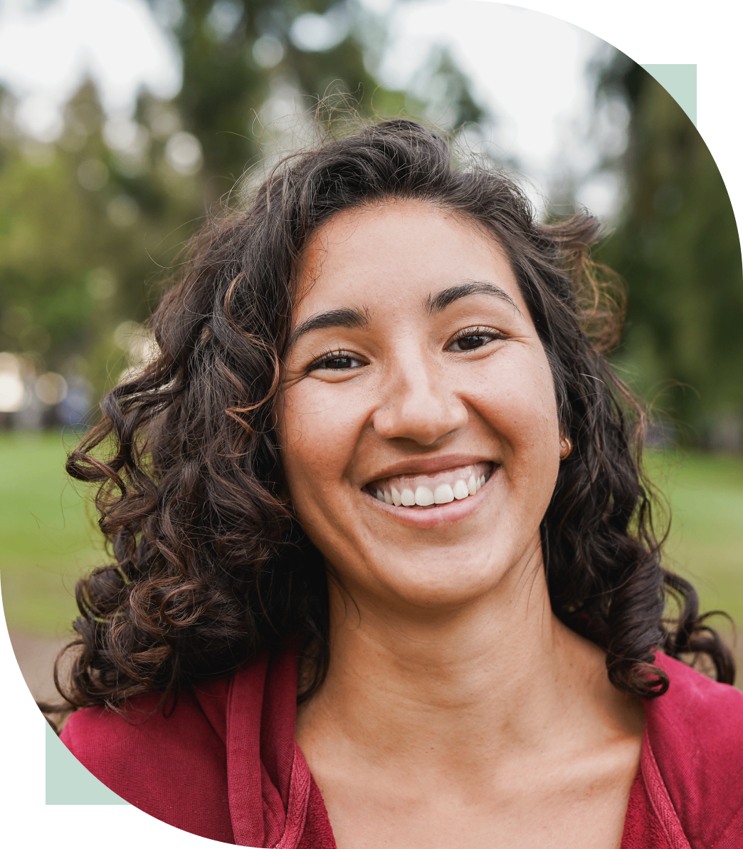 Smiling woman with curly hair outdoors.